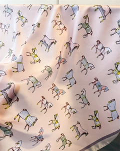 Detailed view of pink silk-like scarf featuring intricate equestrian horse print patterns