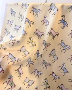 Detail of silk-like scarf featuring horse print patterns and smooth glossy texture
