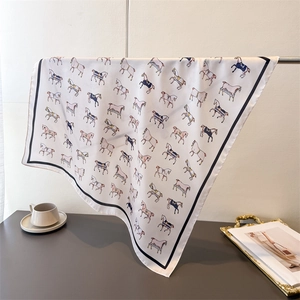 Detail shot of silk-like scarf featuring horse print patterns and black borders