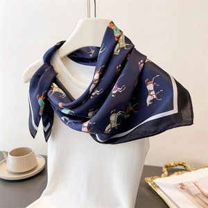 Detail view of dark blue silk scarf with horse print tied on a white knitted vest