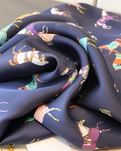 Detail of silk scarf showing equestrian horse print and luxurious satin texture