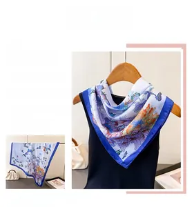 Detail of silk-like square scarf featuring colorful butterfly prints and dark blue borders