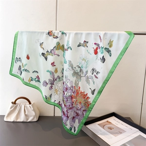 Detail of silk square scarf showing vibrant butterfly and floral prints with satin sheen