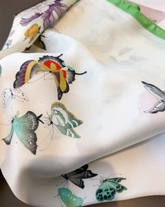Detail of silk satin scarf with colorful butterfly patterns and green rolled edges