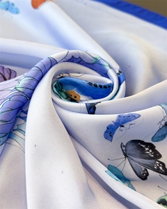 Macro view of blue butterfly print on a glossy satin silk square scarf texture