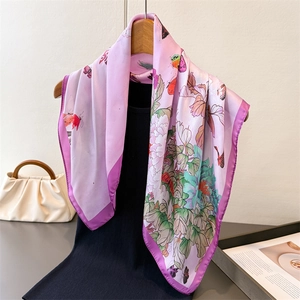 Pink silk-like square scarf with butterfly and peony print on a wooden hanger