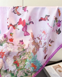 Detailed view of pink floral silk scarf with butterfly print and purple rolled edges