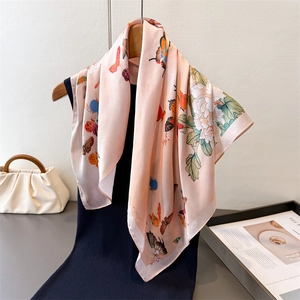 Pink silk square scarf with butterfly and floral print hanging on a wooden hanger
