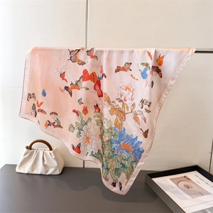 Detailed view of pink silk scarf with floral butterfly prints draped on a metal rack