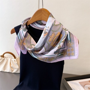 Detail of silk-like square scarf with horse chain print and crown patterns