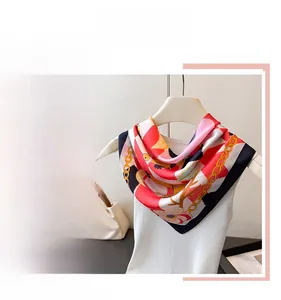 Detailed close-up of a luxury silk square scarf with chain and floral print patterns