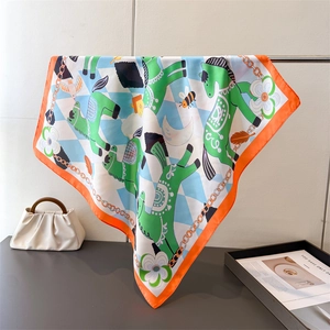 Detail of silk square scarf with horse chain print and orange edges hanging on a metal rod
