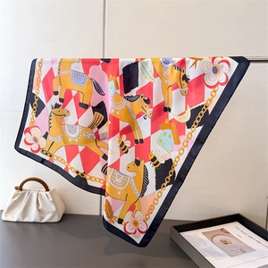 Close-up of silk-feel square scarf featuring carousel horse print and gold chain patterns