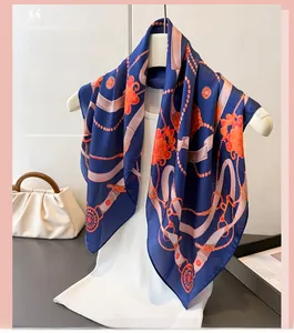 Detailed texture of silk scarf featuring dark blue base with orange floral and chain patterns