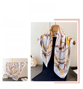 Detail of horsebit and chain print on white silk scarf with leather pattern elements