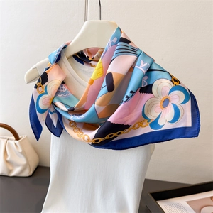 Detailed view of horse print silk scarf tied on a white vest with chain patterns
