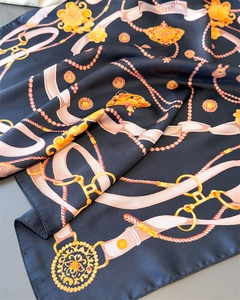 Detailed close-up of navy satin scarf with luxury gold chain and jewel prints