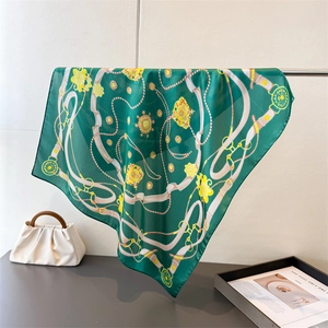 Close-up of dark green silk scarf featuring golden chain print and vintage buckle patterns