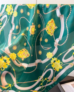 Detail of silk-like scarf featuring emerald green base with vintage gold chain prints