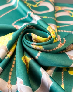 Macro shot of emerald satin scarf with golden chain print and smooth silk texture