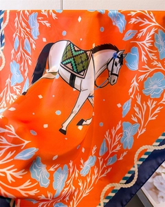 Detail of silk scarf showing equestrian horse print with coral and floral patterns