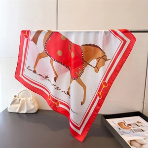 Détail d'un foulard en soie rouge et blanc avec motif équestre de cheval et de chaînes