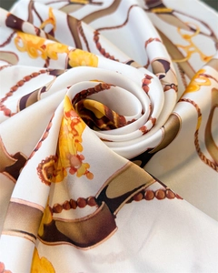 Detail of silk scarf with golden chain print showing smooth texture and soft sheen