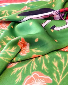 Detailed macro view of green silk scarf featuring vibrant floral and character prints
