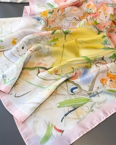 Close-up of artistic floral print silk scarf with pink rolled edges and satin finish