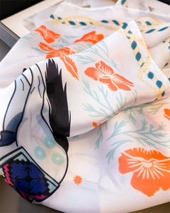 Detailed view of white silk scarf featuring orange floral prints and nautical rope pattern
