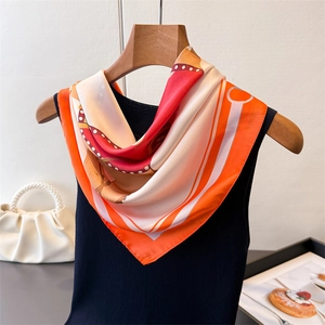Gros plan d'un foulard en soie aux imprimés de chaînes orange et rouge sur cintre