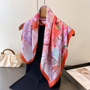 Artistic oil painting floral silk scarf draped on a hanger with orange contrast edges