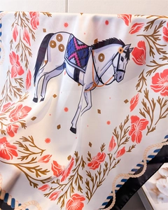 Macro detail of satin silk scarf showing luxury white horse print and rope patterns