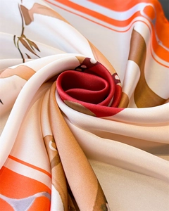 Vue macro d'un foulard soyeux avec imprimé chaîne dans les tons orange, rouge et brun