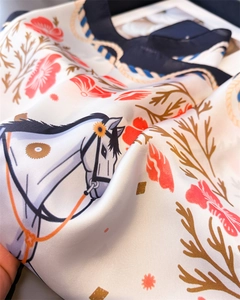 Detail of silk-like scarf featuring equestrian horse print and floral patterns