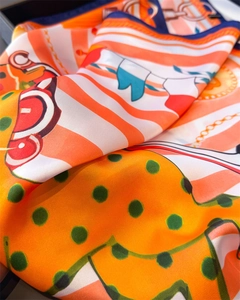 Detailed close-up of equestrian silk scarf with orange and blue horse bit prints
