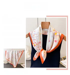 Detail of elegant floral silk scarf with vibrant orange border and artistic patterns