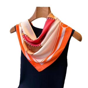 Foulard en soie à imprimé équestre orange et rouge suspendu sur un cintre en bois