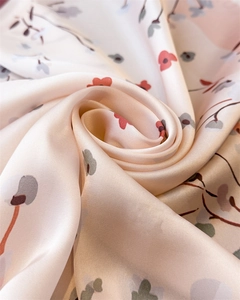 Macro shot of light pink satin scarf with delicate red and gray floral pattern texture
