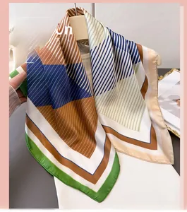 Detail of geometric stripe silk scarf hanging on a white hanger with fashion accessories