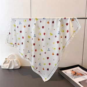 Élégant foulard en soie beige avec motifs floraux colorés suspendu sur un support