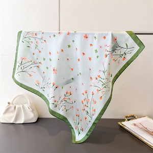 Detailed view of floral silk scarf styled with a pearl handbag and golden tray