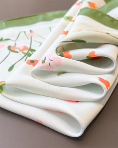 Macro detail of silky printed floral scarf fabric showing light green texture and pink petals