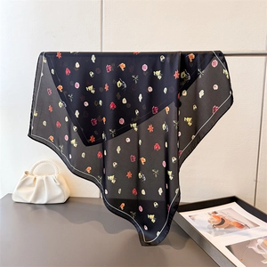 Élégant foulard en soie noir aux imprimés floraux colorés drapé sur un support en métal