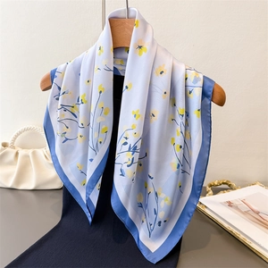 Elegant floral print silk scarf in light blue and yellow hanging on a wooden hook