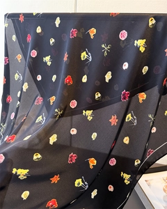 Détail du foulard en soie à fleurs noires montrant la texture fluide et légère