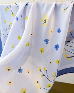 Macro detail of silky light blue fabric featuring yellow and navy floral patterns