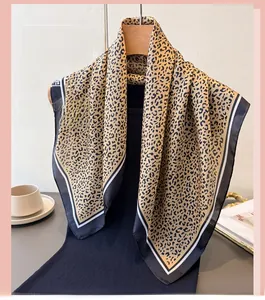 Detailed view of leopard print silk scarf with contrast striped edges on a hanger