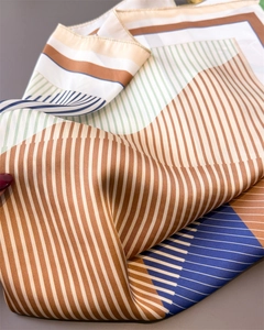Detail of geometric stripe pattern and fine rolled hem on the glossy silk-like scarf
