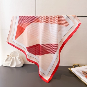 Detail view of geometric silk scarf with red rolled edges draped on a metal stand